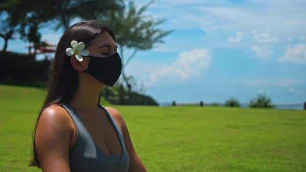 유럽의 소녀는 얼굴에 보호용 마스크를 연꽃을 풀밭에 속에서 요가를 — 비디오