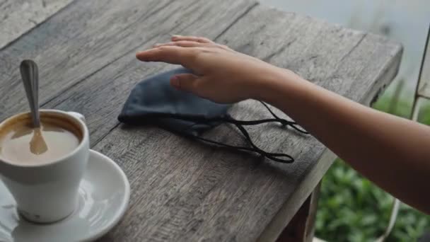 유럽의 소녀는 공공장소에 식탁에 앉아서 양손으로 탁자에서 부드러운 검은색 보호용 — 비디오