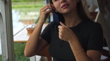 Genç Avrupalı esmer bir kız halka açık bir masada oturuyor ve yüzüne siyah koruyucu bir maske takıyor.