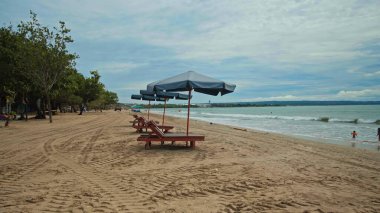 Sabahın erken saatlerinde sahilde katlanmış plaj şemsiyeleri ve boş güneşlikler.