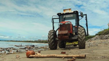 Kuta, Badung, Bali, Kuta Beach Endonezya - 4 Ocak 2021: Kuta kentindeki Bali adasında denizden plastik çöp attıktan sonra kumdaki deniz plajlarını temizleyen traktör teknisyeni