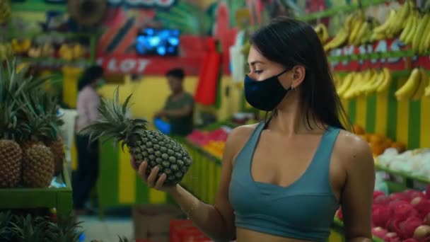 一个年轻的欧洲姑娘在手里拿着菠萝的商店里挑选有机水果 — 图库视频影像
