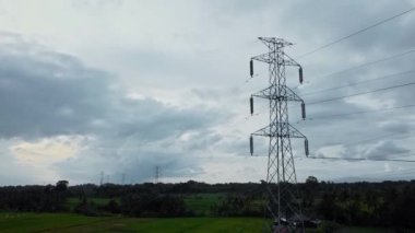 Gün batımında yeşil pirinç tarlasında yeni inşa edilmiş bir elektrik iletim kulesinin hava aracı görüntüsü.