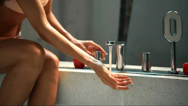風呂に座っている若いヨーロッパの女の子は彼女の手でバスルームに水でタップを開きます — ストック写真