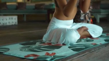 Genç Avrupalı esmer bir kız havlunun üzerinde oturuyor ve dinlenme odasında yoga yapıyor.