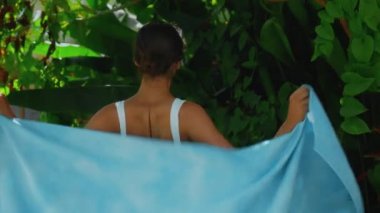 Genç Avrupalı esmer kız arka bahçesinde yeşil bahçeli bir havluyu siler.