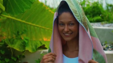 Genç Avrupalı esmer kız arka bahçesinde yeşil bahçeli bir havluyu siler.