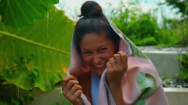 Genç Avrupalı esmer kız arka bahçesinde yeşil bahçeli bir havluyu siler.