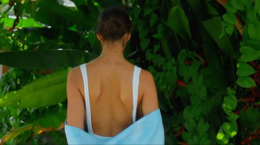 Genç Avrupalı esmer kız arka bahçesinde yeşil bahçeli bir havluyu siler.