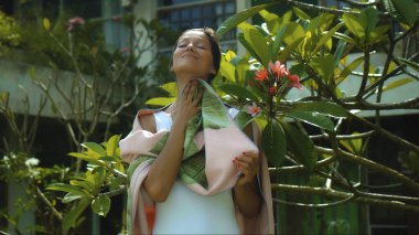 Genç Avrupalı esmer kız arka bahçesinde yeşil bahçeli bir havluyu siler.