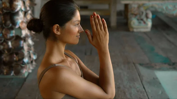 A young European brunette girl sits on a towel and is engaged in yoga in the lounge room