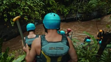 Ubud, Gayiar, Kabupaten Badung, Bali, Endonezya - 22 Mayıs 2021: Sarı çizgili siyah koruyucu ceketler ve rafting için koruyucu miğferlerle merdivenlerden inen insanlar