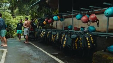 Ubud, Gayiar, Kabupaten Badung, Bali, Endonezya - 22 Mayıs 2021: Sarı çizgili siyah koruyucu ceketler ve sokakta duvara asılı rafting çalışması yapmak için koruyucu kasklar