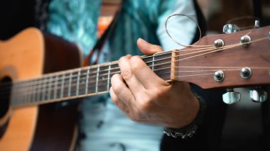 Genç adam, mikrofon kullanarak klasik bir akustik ahşap gitarla el ele oynuyor.