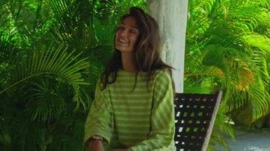 Uzun, kırmızı kıvrımlı, yeşil bahçeli, mavi temiz su havuzlu ve güzel yeşil elbiseli, mavi gökyüzü olan genç, saçları olan bir kız.