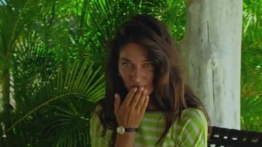 Uzun, kırmızı kıvrımlı, yeşil bahçeli, mavi temiz su havuzlu ve güzel yeşil elbiseli, mavi gökyüzü olan genç, saçları olan bir kız.