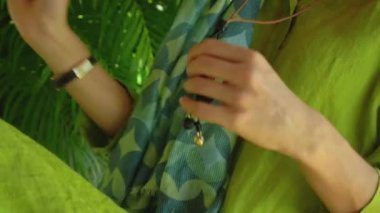 Genç bir kız yeşil bir elbiseye dokunuyor ve elini arka bahçedeki bankta oturuyor.