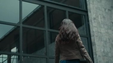 Genç, güzel, neşeli Avrupalı uzun saçlı esmer kız sokakta yürüyor ve dönüyor.