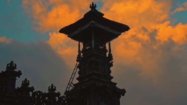 夕暮れ時を背景に赤い雲と青い空の暗い夜に藁屋根の古いインドネシアの民族の建物 — ストック動画