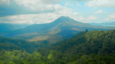 Endonezya 'daki yeşil ağaçlı ve yüksek bulutlu Batur volkanı manzarası
