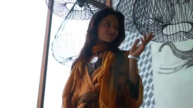 Genç güzel Avrupalı uzun saçlı esmer kız avizenin yanında duruyor ve elleriyle ona dokunuyor.