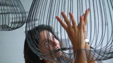 Genç güzel Avrupalı uzun saçlı esmer kız avizenin yanında duruyor ve elleriyle ona dokunuyor.