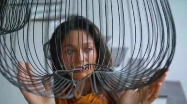 Genç güzel Avrupalı uzun saçlı esmer kız avizenin yanında duruyor ve elleriyle ona dokunuyor.