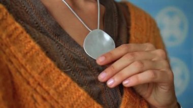 Sarı kazaklı genç ve güzel bir Avrupalı kız bir odada oturur ve elleriyle boynunda asılı bir takıya dokunur.