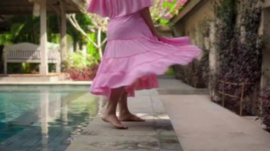 Genç Avrupalı hamile kız arka bahçede pembe elbiseli yeşil bir bahçede kalıyor.