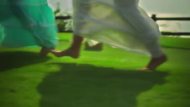 穿着长裙的年轻欧洲姑娘的腿 光着脚在绿草上走在圆圈里 — 图库视频影像