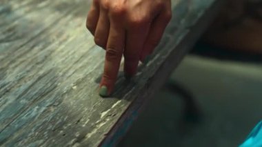 Genç Avrupalı bir kız ahşap bir masada oturuyor ve parmaklarıyla masada oynuyor. Tıpkı bu yürüyen adam gibi.