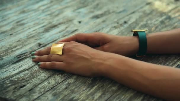 若いヨーロッパの女の子は木製のテーブルに座って 黄金のリングで彼に手を置き 腕時計 — ストック動画