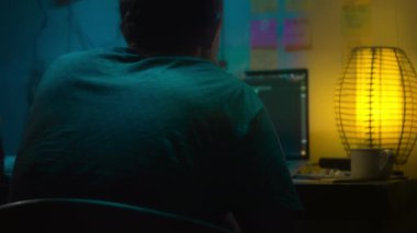 Avrupalı bir kripto tüccarı karanlık bir odada, elinde neon ışığı olan bir dizüstü bilgisayarın arkasında oturur, kripto döviz değişimindeki fiyat hareketlerinin grafiklerini gösteren bir ekrana bakar. Bir sigara içiyor. Bulanık arkaplan