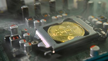 Karanlıkta ışık ve duman olan elektronik bileşenleri olan ana kartta merkezi bir işlemci yerine parlayan ve yansıtan altın bir Bitcoin. Bitcoin Madencilik