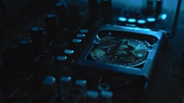 Karanlıkta ışık ve duman olan elektronik bileşenleri olan ana kartta merkezi bir işlemci yerine parlayan ve yansıtan altın bir Bitcoin. Bitcoin Madencilik