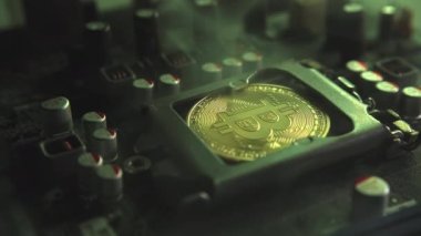 Karanlıkta ışık ve duman olan elektronik bileşenleri olan ana kartta merkezi bir işlemci yerine parlayan ve yansıtan altın bir Bitcoin. Bitcoin Madencilik