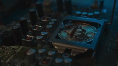 Karanlıkta ışık ve duman olan elektronik bileşenleri olan ana kartta merkezi bir işlemci yerine parlayan ve yansıtan altın bir Bitcoin. Bitcoin Madencilik
