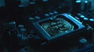 Karanlıkta ışık ve duman olan elektronik bileşenleri olan ana kartta merkezi bir işlemci yerine parlayan ve yansıtan altın bir Bitcoin. Bitcoin Madencilik
