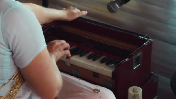 木製の床に座ってキーボードの民族楽器のハーモニウムを演奏する少女 — ストック動画