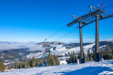 Slovak kayak merkezi Jasna. Kar güneşte parlar. Dağ zirveleri arasında mavi gökyüzü ve hafif sis. Sandalye kaldırma