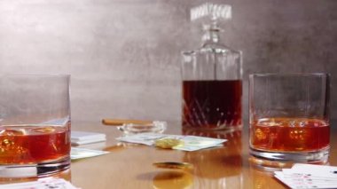 Cilalanmış ahşap masa. İki bardakta buzlu viski. Dolar banknotları. Kül tablasında sigara. Kağıt oynuyorum. Bitcoin merkezde döner. Yavaş çekim