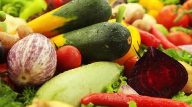 Yakın plan taze sebzeler: lahana, havuç, mısır, salatalık, sarımsak, soğan, biber, patates, salata, domates, mantar. Kamera yavaş hareket ediyor.