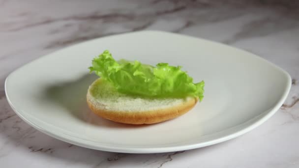 Weißer Teller Auf Einem Marmortisch Ein Blatt Salat Fällt Auf — Stockvideo