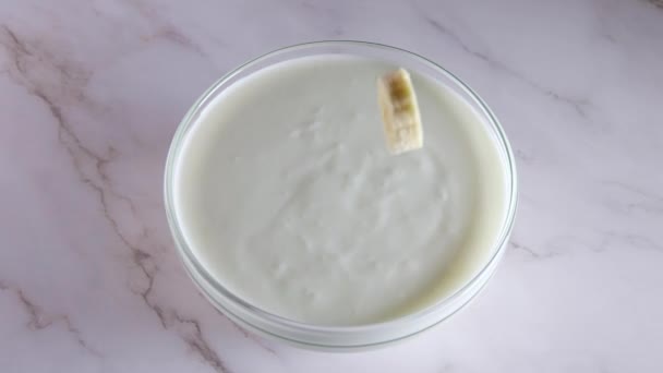 Ciotola Vetro Con Yogurt Tavolo Marmo Due Fette Banana Cadono — Video Stock