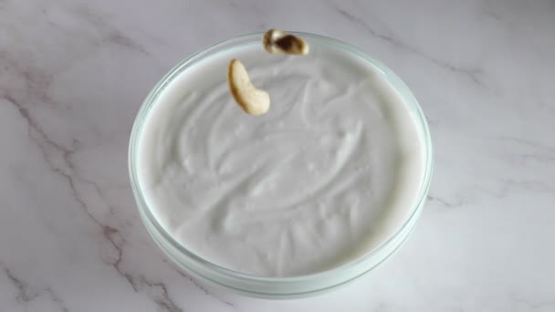 Glazen Kom Met Yoghurt Een Marmeren Tafel Een Paar Cashewnoten — Stockvideo