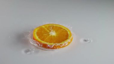 İnce katmanlı beyaz masa. Bir dilim sulu portakal düşer ve bir sürü sıçrama yaratır. Yavaş çekim