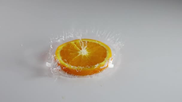 Capa Delgada Agua Sobre Una Mesa Blanca Pedazo Naranja Jugosa — Vídeos de Stock