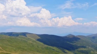 Güneşli bir günde ağaçsız yaz tepeleri. Bulutlar hızla akar ve gölgeler yaratır. Hızlı hareket