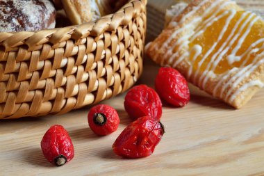 Kurumuş gül ağacı meyvesi ve çikolatalı zencefilli ekmek sepetinde ahşap bir arka planda.