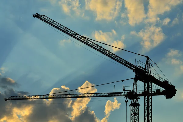 Construction cranes against of the sun — Stock Photo, Image